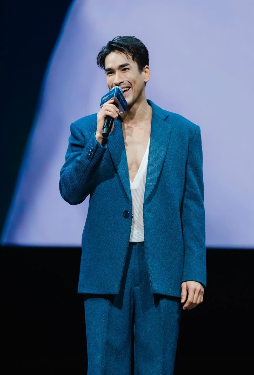 Nadech Kugimiya laughing into a microphone on stage