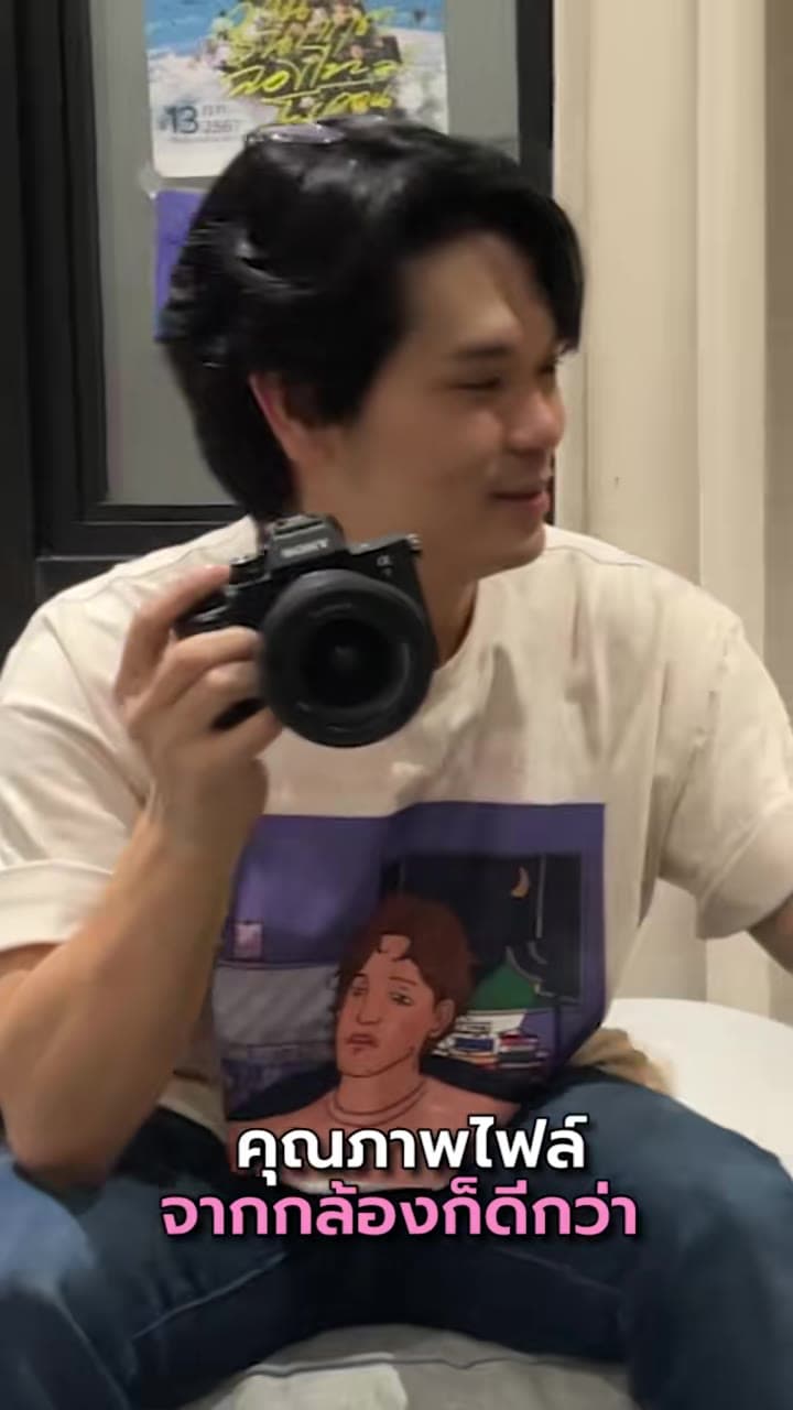 เทพลีลา นั่งบนโซฟา ถือกล้อง Sony Alpha แนบอก มองไปด้านข้าง
